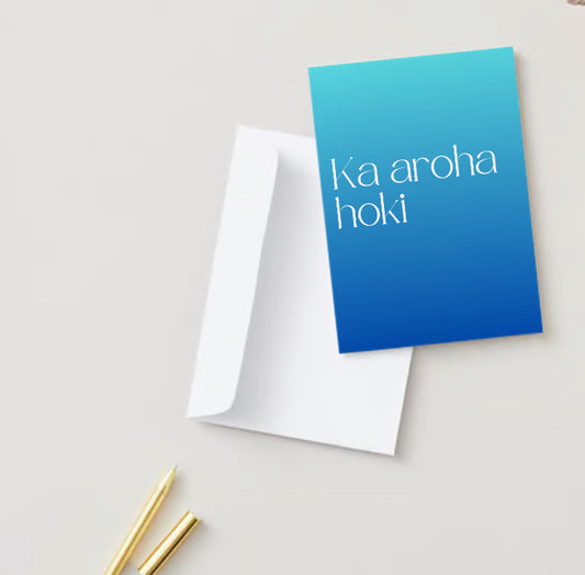 Te Reo Māori Card - Ka Aroha Hoki This is a flat lay of the card. It has blue gradient cover and white text reading "ka aroha hoki". The card is sitting on top of a white envelope. 